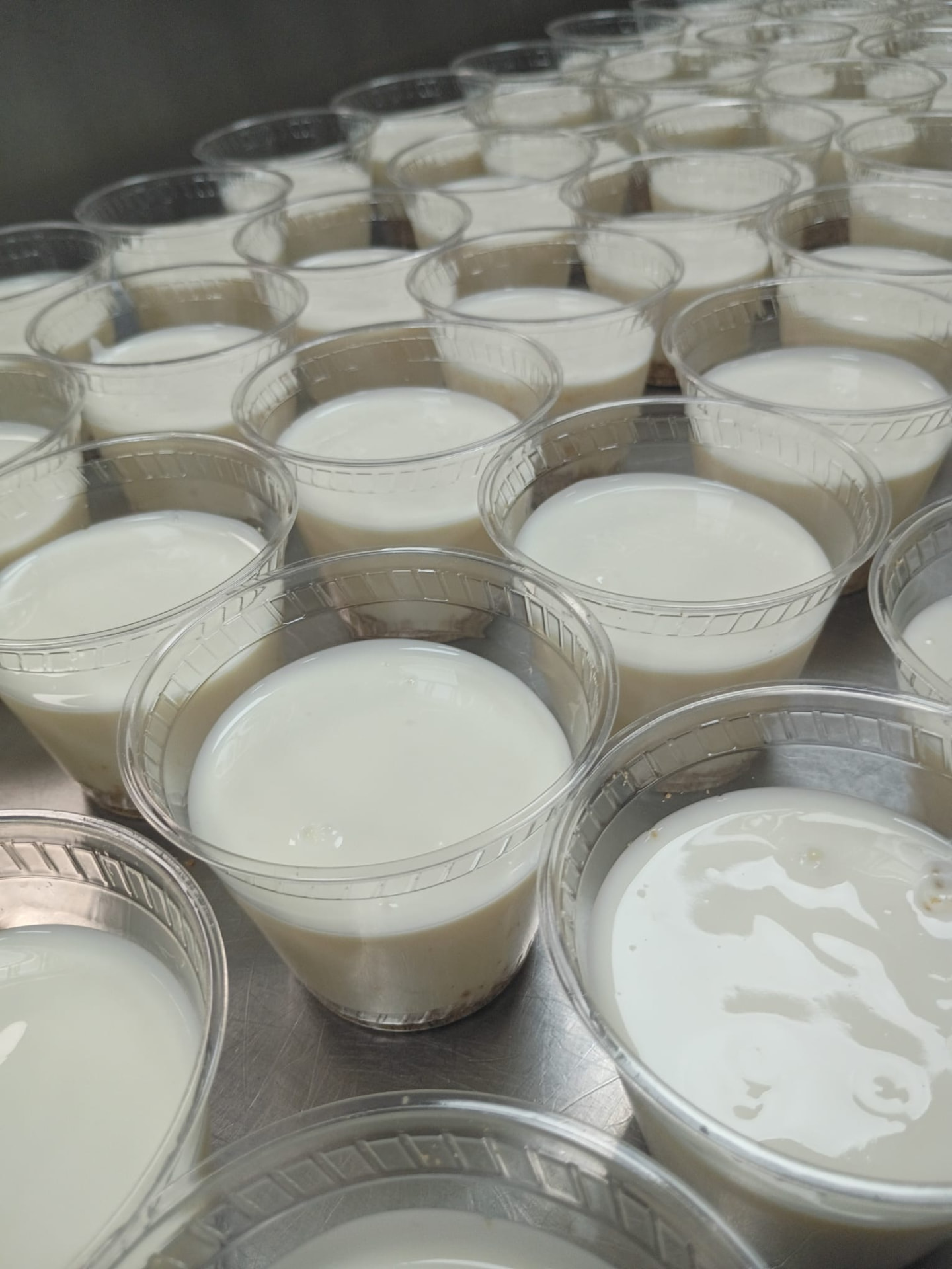 Vasos de yogur artesanal recién preparados en la mesa de acero del taller